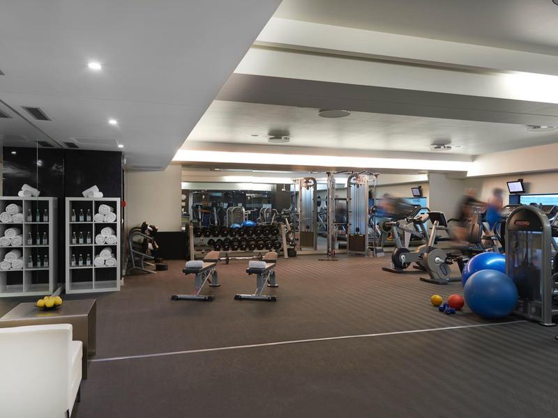 Großer Fitnessraum mit Gewichten, Hanteln, Spiegeln und Trainingsbällen in modernem Design.