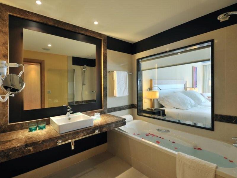 Modernes Badezimmer mit großer Badewanne, Waschbecken auf Marmorplatte und Fenster zum Schlafzimmer.