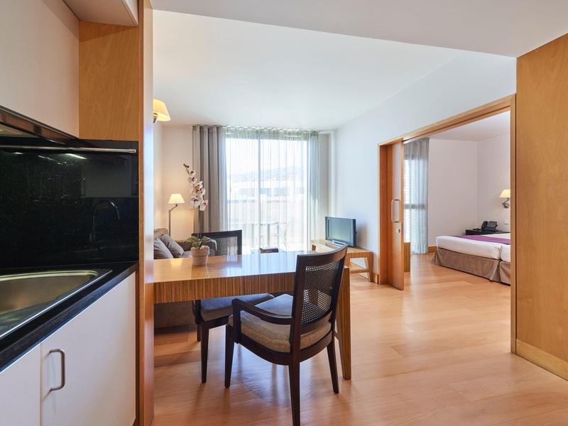 Area moderna della camera d'hotel con scrivania, sedie e una camera da letto sullo sfondo.