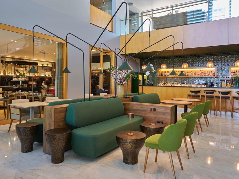 Lounge di hotel moderno con sedie e divani verdi, area bar sullo sfondo