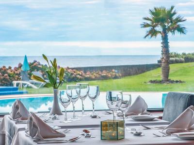 Tavolo apparecchiato con bicchieri da vino, vista su piscina, palma e oceano.