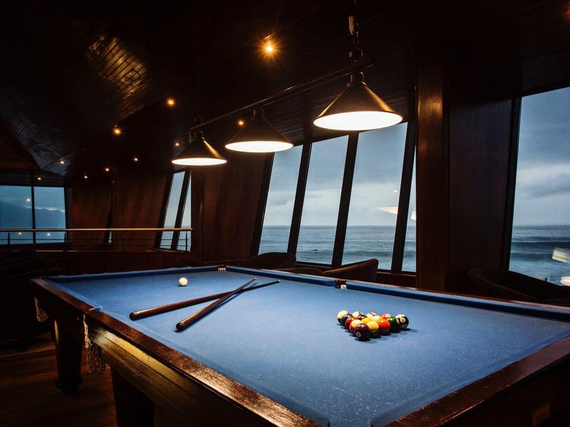 Sala giochi accogliente con tavolo da biliardo e ampie finestre che mostrano un cielo nuvoloso.