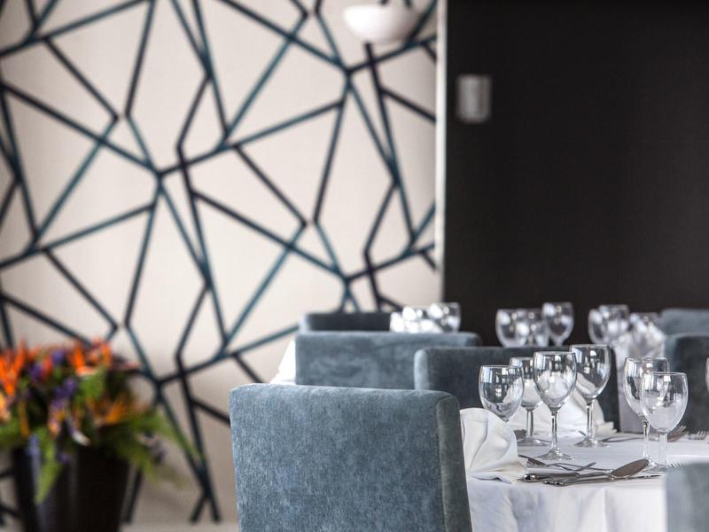 Tavolo da pranzo elegante con bicchieri da vino e centrotavola floreale in una stanza elegante.