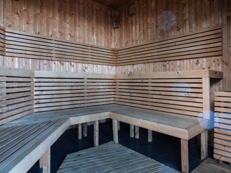 Interno di sauna in legno con panche a gradini e illuminazione calda.