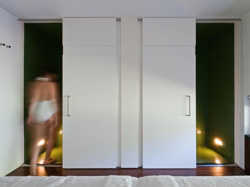 Due porte scorrevoli bianche in un interno moderno, una parzialmente aperta con una persona sfocata.