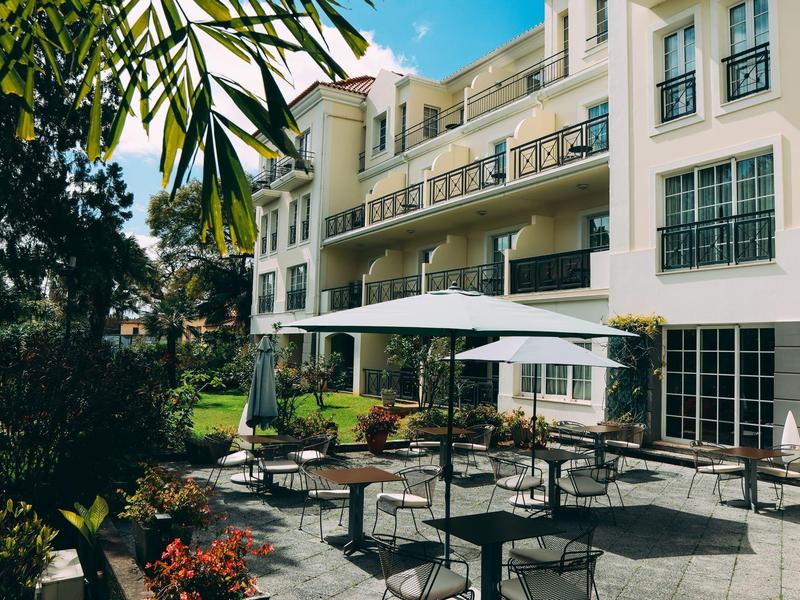 Area esterna di un hotel con tavoli, sedie e ombrelloni sulla terrazza.