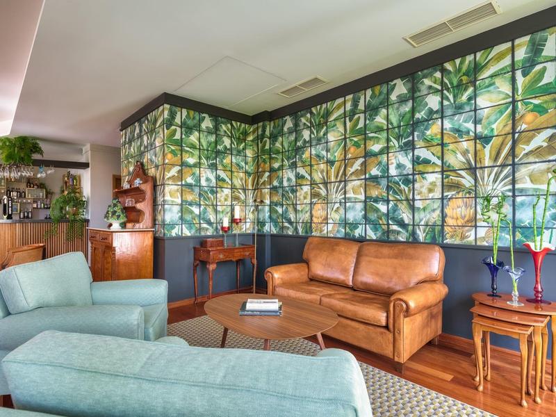 Lounge dell'hotel moderna con decorazione murale di piante Panama, divano in pelle e poltrone blu.