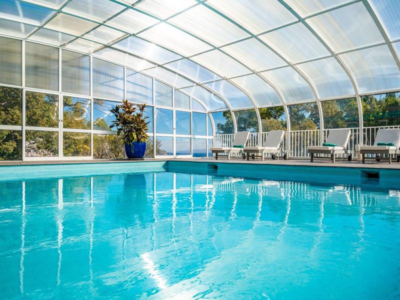 Piscina interna riscaldata con tetto curvo trasparente e sdraio in hotel