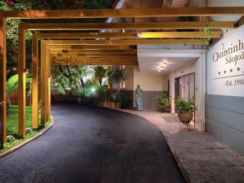 Ingresso dell'hotel illuminato con struttura in legno e sentiero lastricato di notte.