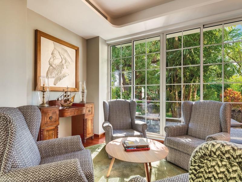 Accogliente zona soggiorno con poltrone, camino e grandi finestre con vista sul giardino.