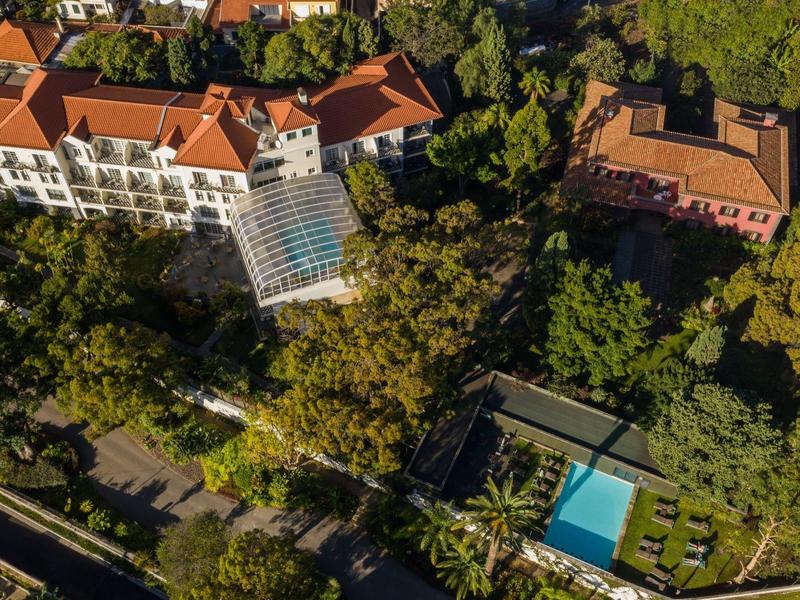 Veduta aerea di un hotel con tetti rossi, circondato da alberi e una piscina.