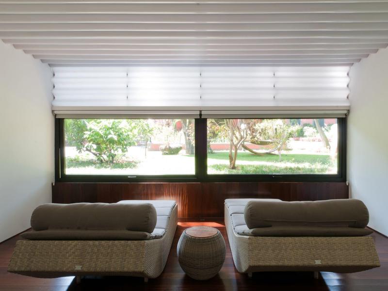 Camera moderna con due divani, un piccolo tavolo rotondo e grandi finestre con vista sul verde.