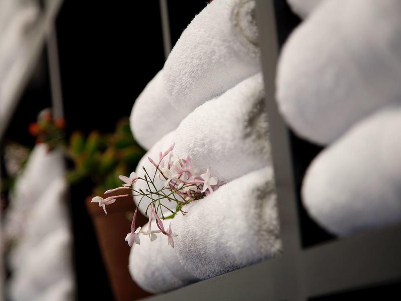 Asciugamani bianchi piegati su una mensola con decorazione floreale.