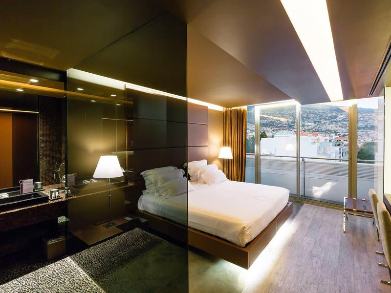 Chambre d'hôtel moderne avec lit double, lampes et grande fenêtre donnant sur l'eau.