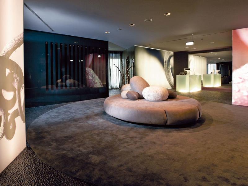 Chambre d'hôtel moderne avec éclairage abstrait et coin salon rond aux couleurs atténuées.