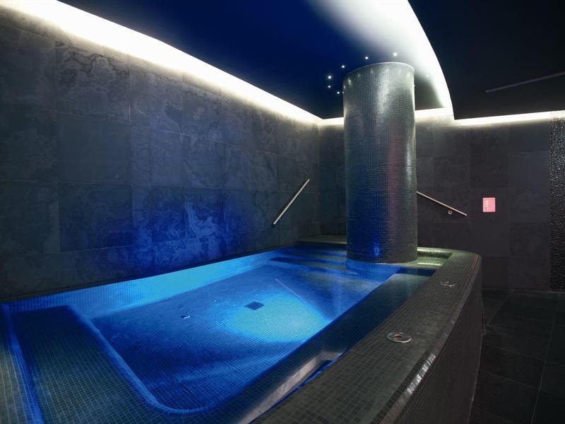 Bain à remous moderne avec éclairage LED bleu dans une salle de spa sombre