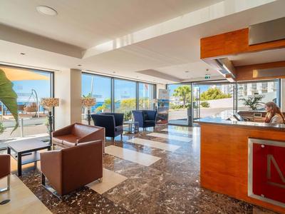 Helles Hotelzimmer mit großen Fenstern, Ledersesseln, Marmorfußboden und Meerblick.