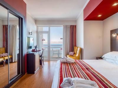 Modernes Hotelzimmer mit Doppelbett, Balkon, Schrank mit Spiegeln und Stühlen in warmen Farben.