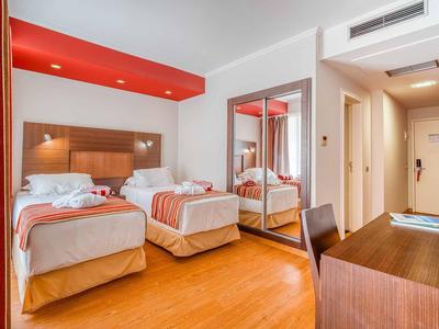 Modernes Hotelzimmer mit zwei Einzelbetten, Holzboden und großem Spiegelkleiderschrank.