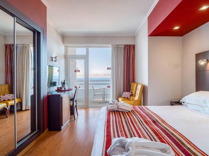 Modernes Hotelzimmer mit Doppelbett, Balkon, Schrank mit Spiegeln und Stühlen in warmen Farben.