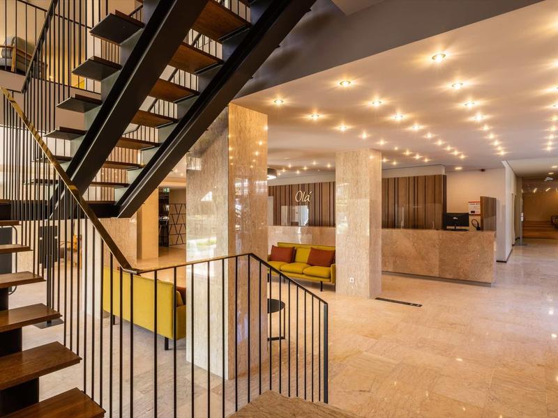 Moderner Innenraum mit Treppe aus Holz und Metall, heller Marmorboden und warmen Deckenlichtern.