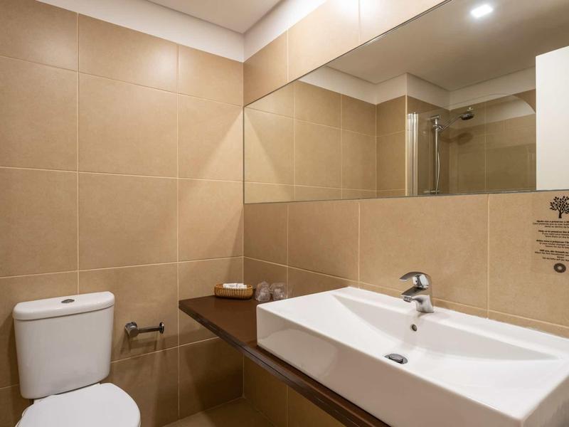 Kompaktes Badezimmer mit rechteckigem Waschbecken, Toilette und großem Wandspiegel.