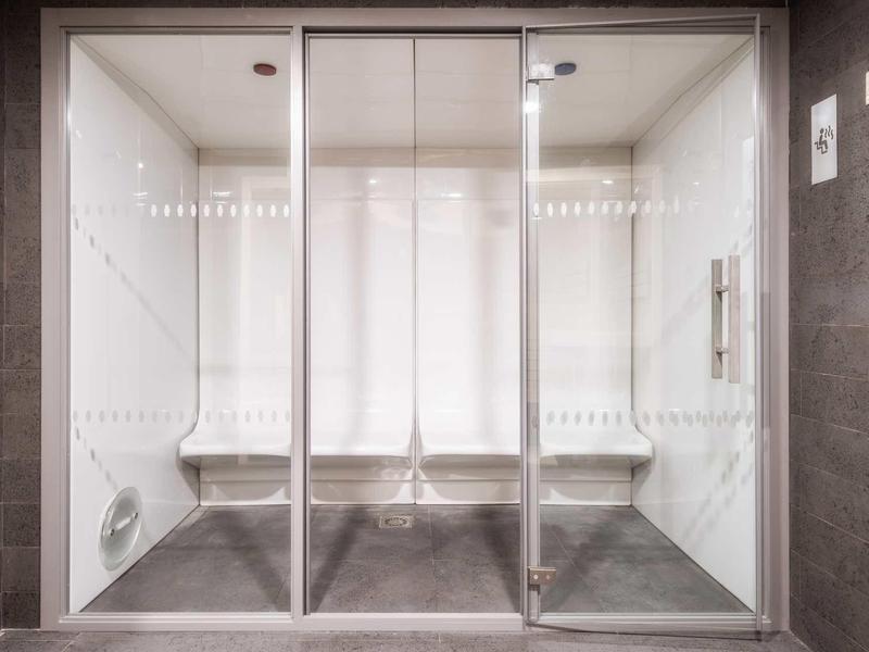 Moderne Duschkabine mit dreiteiliger Glastür und weißen Wandfliesen in schlichtem Design.