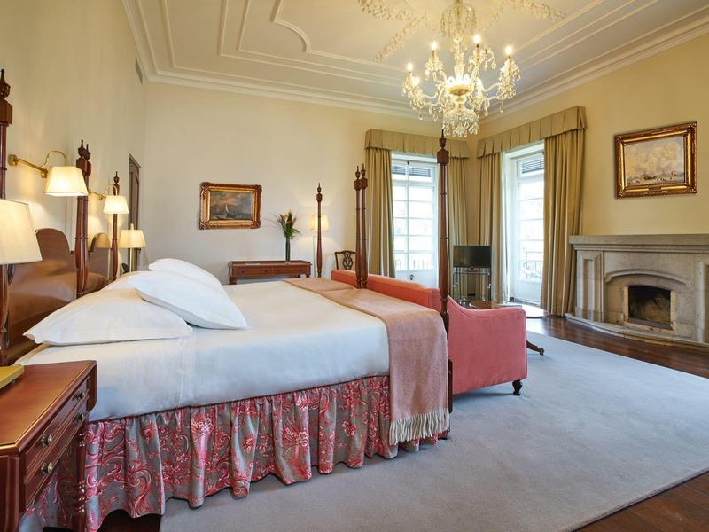 Camera d'albergo elegante con lampadario, camino e letti confortevoli con struttura in legno.