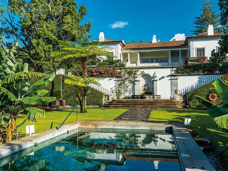 Hotel di lusso con piscina e giardino rigoglioso sotto un cielo azzurro