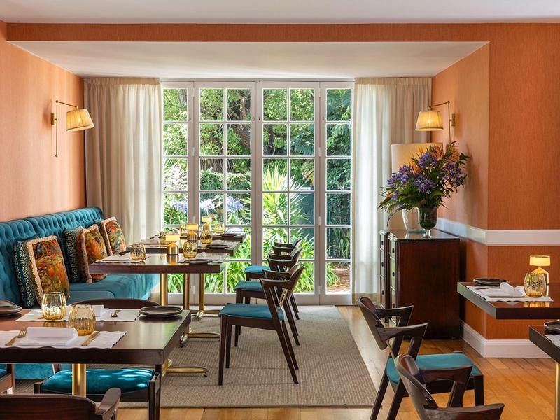 Ristorante luminoso con grandi finestre, parquet e arredi moderni.