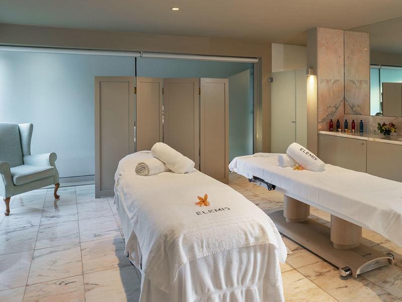 Spazio spa elegante con due lettini da massaggio e atmosfera tranquilla.