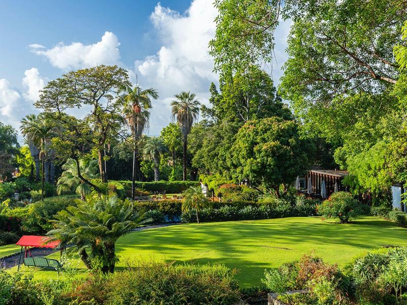 Campo da golf verde circondato da alberi sotto un cielo azzurro in una giornata soleggiata.