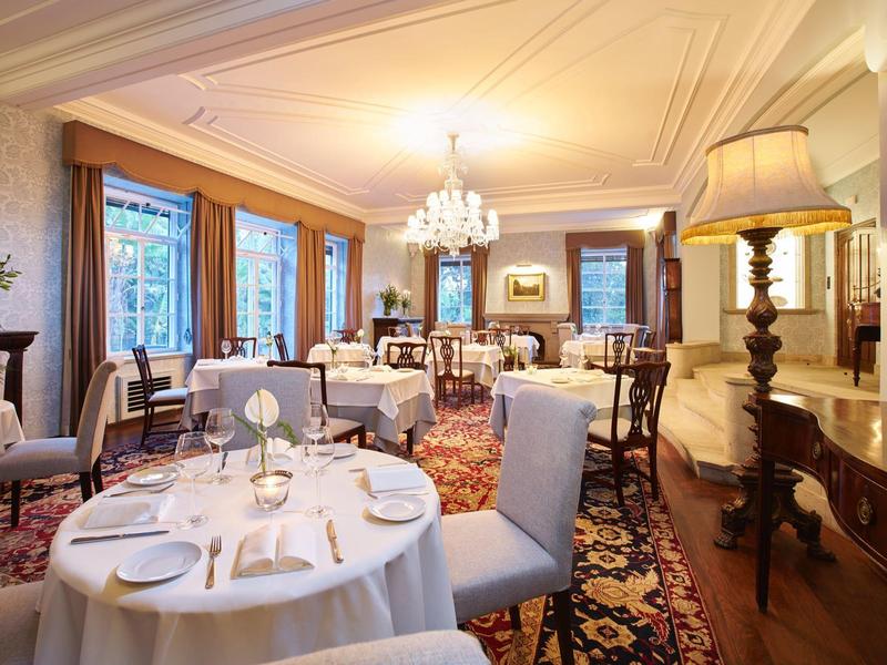 Ristorante elegante con tavoli apparecchiati, lampadario e tappeto sotto luce calda.