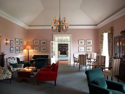 Elegancki salon z różnymi miejscami do siedzenia, pastelowymi ścianami i klasycznym umeblowaniem.