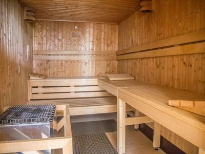 Jasna drewniana sauna wewnętrzna z ławkami i piecem do sauny.