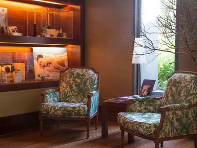 Przytulny kącik z dwoma wzorzystymi fotelami i ciepło oświetloną półką.