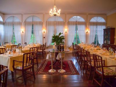 Elegancka restauracja z udekorowanymi stołami, żyrandolem i dużymi oknami z zasłonami