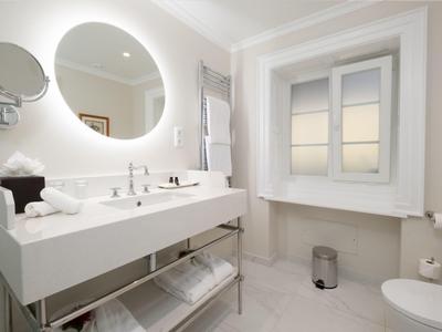 Jasna, nowoczesna łazienka z okrągłym lustrem, białymi ręcznikami i oknem z widokiem.