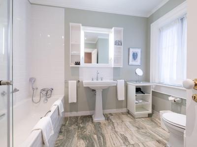 Jasna łazienka z umywalką, lustrem i toaletą, nowoczesne wyposażenie i podłoga drewnopodobna.