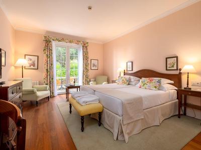 Jasno urządzone pokoje hotelowe z podwójnym łóżkiem, drewnianą podłogą i dostępem do ogrodu