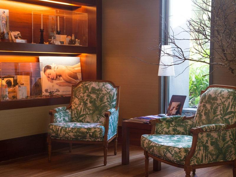 Przytulny kącik z dwoma wzorzystymi fotelami i ciepło oświetloną półką.