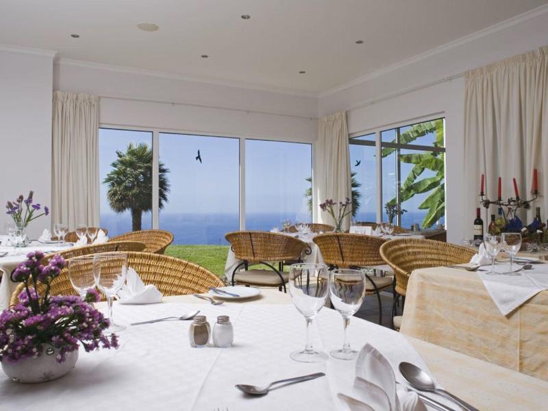 Bright dining room with sea view and set tables for guests.