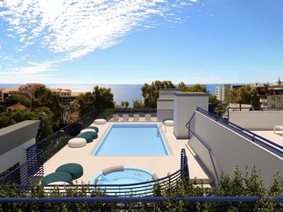 Area piscina sul tetto con lettini e vista sull'oceano sotto un cielo parzialmente nuvoloso.