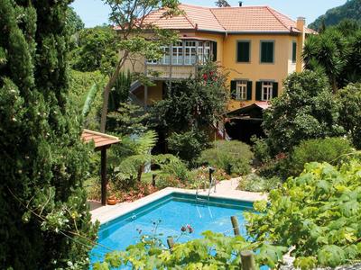 Hotel with yellow building and outdoor pool surrounded by green trees and plants.