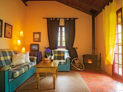 Cozy living room with sofa, fireplace, wooden table, and large windows with yellow curtains.