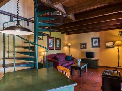 Cozy living room with green table, purple sofa, fireplace, and metal spiral staircase.