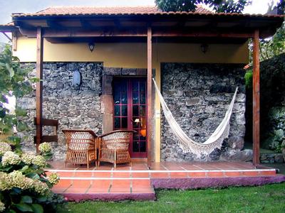 Small terrace with hammock and seating furniture in front of a stone house.