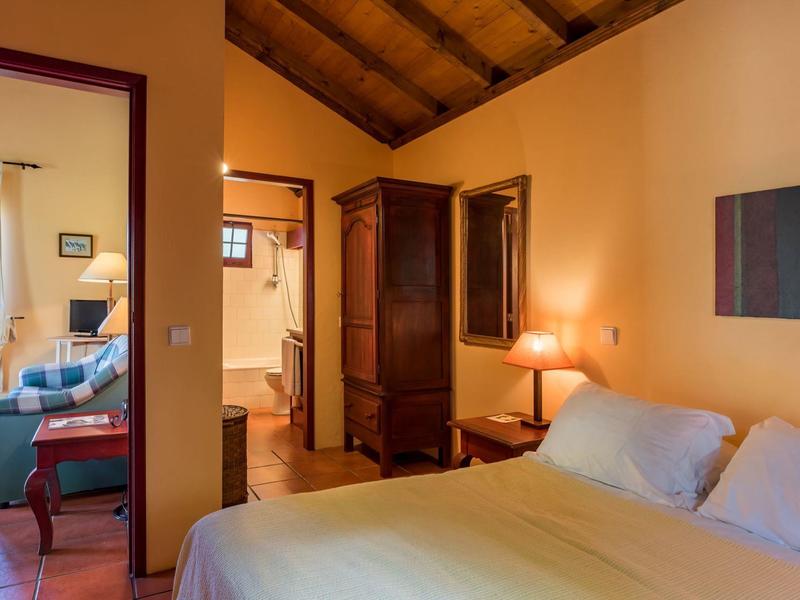 Cozy bedroom with wooden beam ceiling, double bed, and adjoining living room.