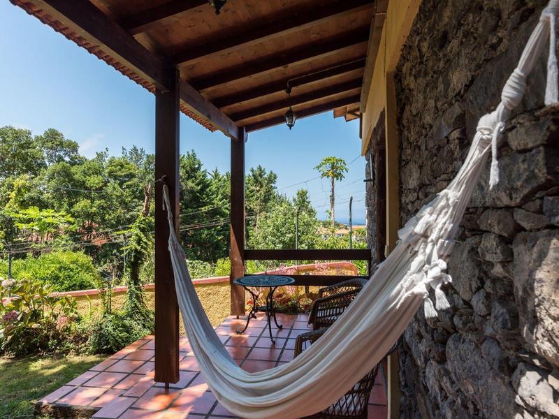 Cozy hammock on a terrace overlooking a green garden.