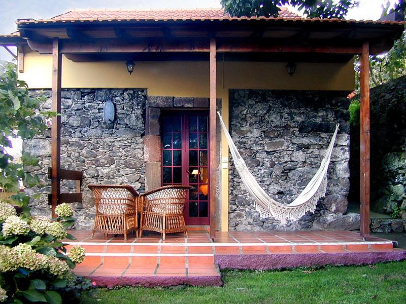 Small terrace with hammock and seating furniture in front of a stone house.